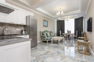 Classic living room and modern kitchen interior with tables against couch and refrigerator on marble floor at home